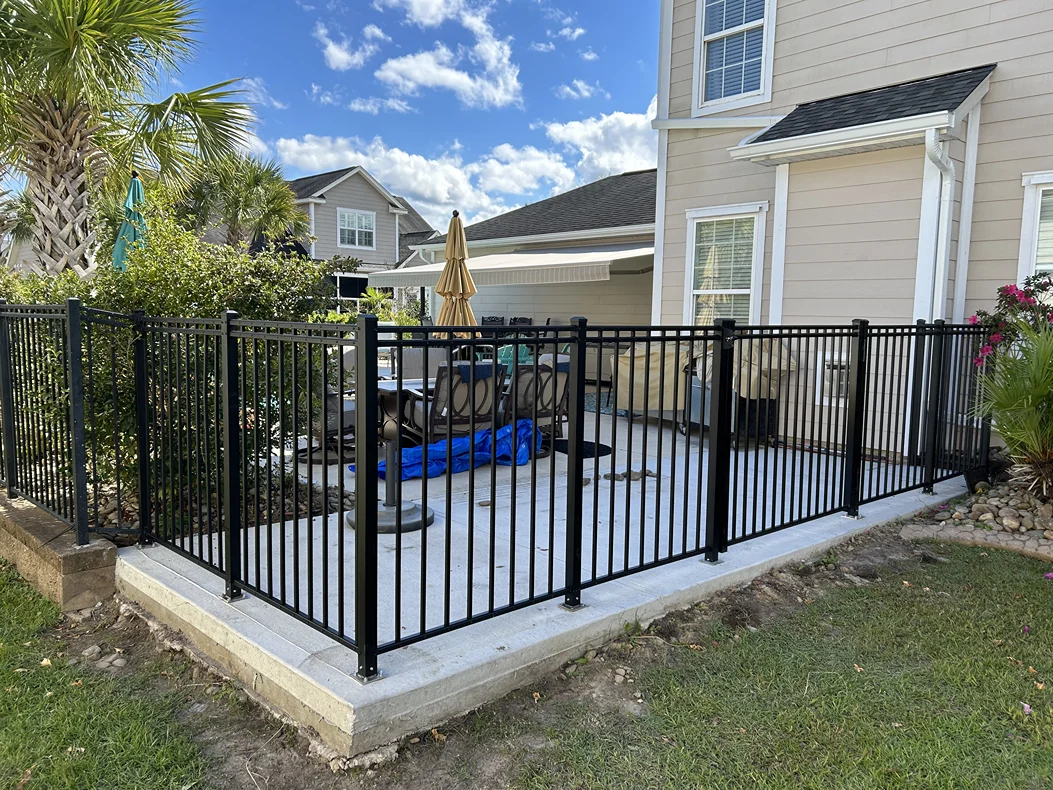 Black aluminum fence enclosing a backyard patio at a residential home in Longs, SC